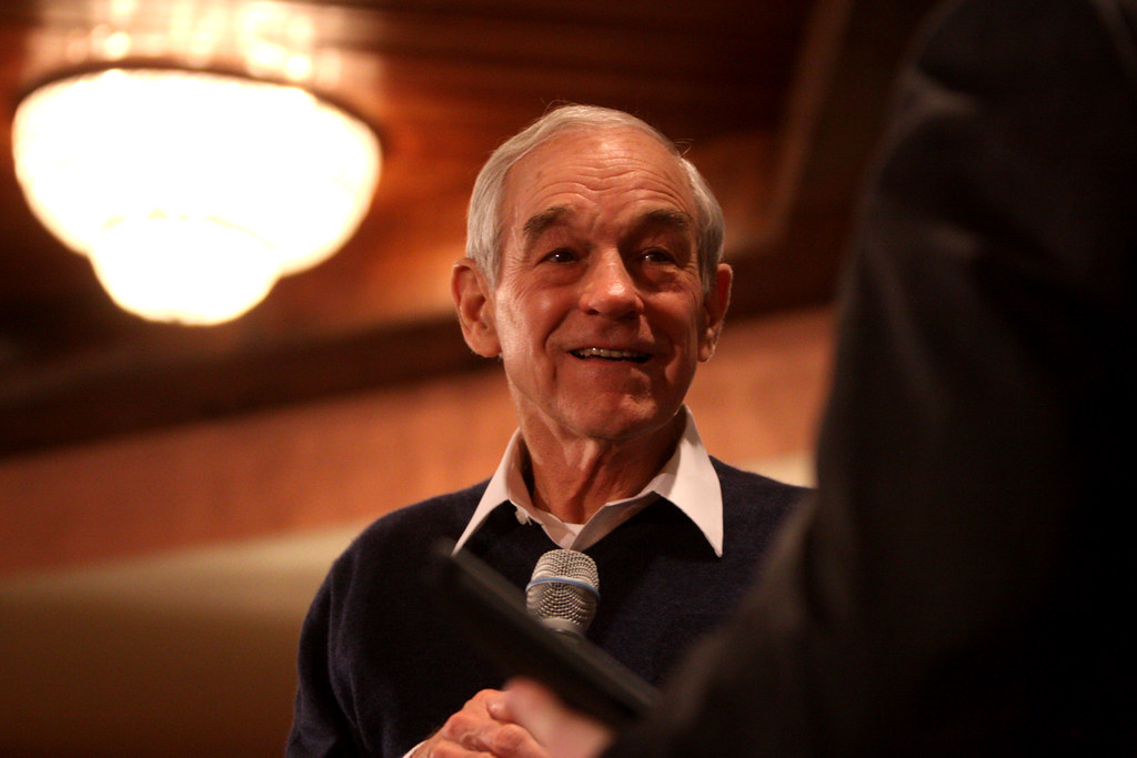 Ron Paul holding a microphone and smiling